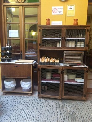 A kitchen area with wooden cabinets, a countertop, and a stove. There are two trash bins under the counter. - Hotel Mezquita (Córdoba)