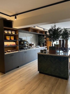 A modern kitchen with built-in shelves, a central island, and a large potted plant. - Hotel Gorinchem (Gorinchem)