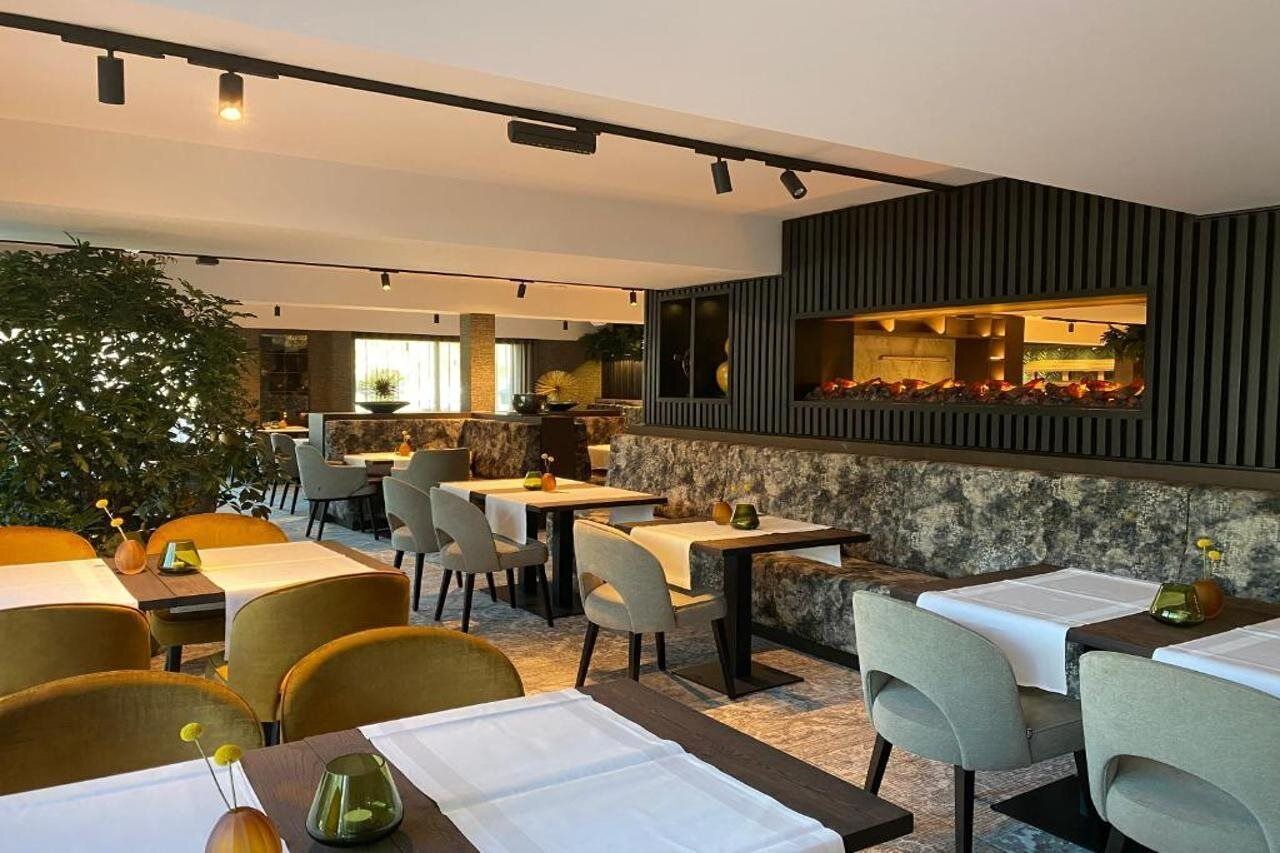 Un ristorante moderno con tavoli, sedie, un'area bar e una pianta grande.
