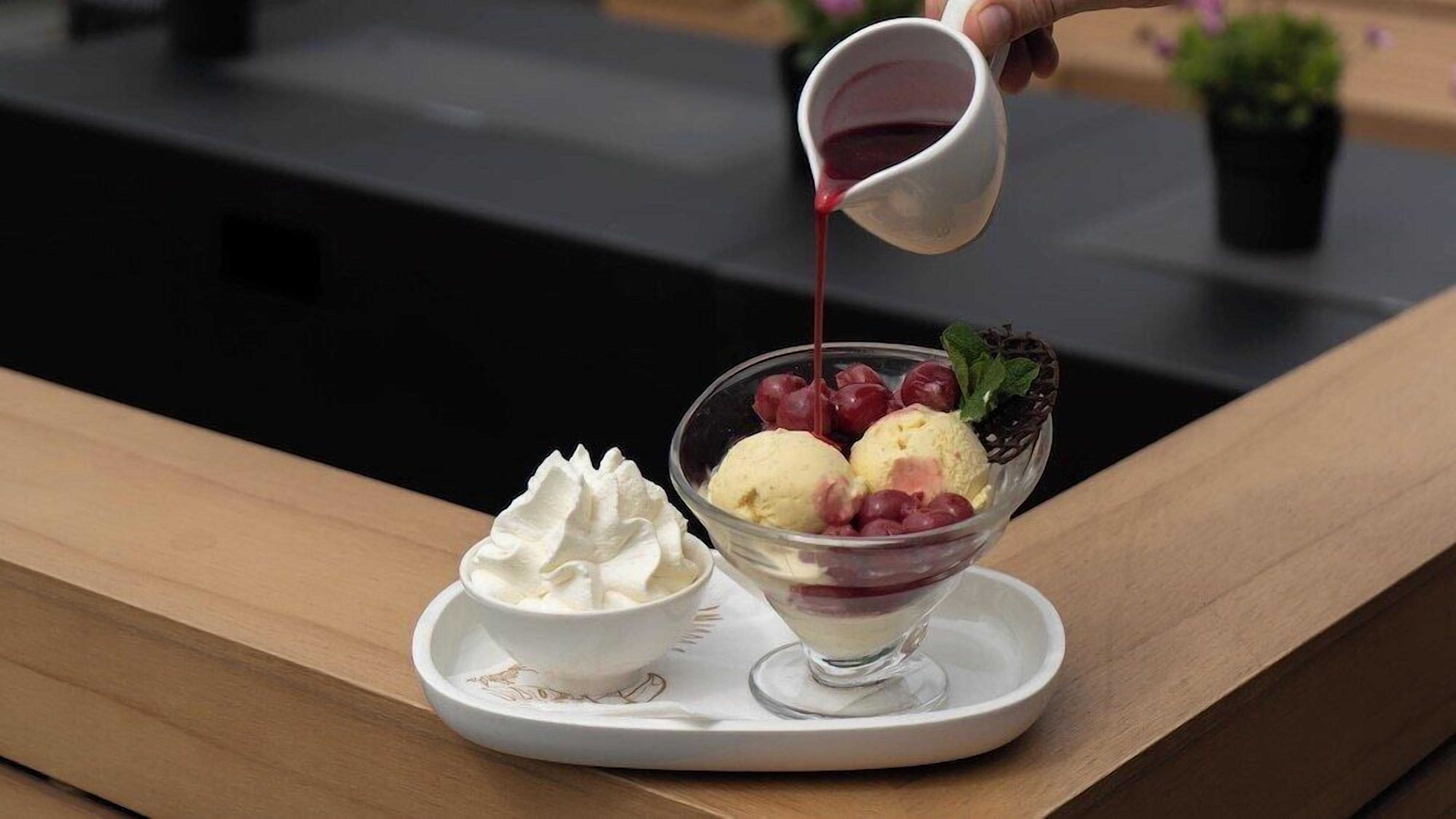 A dessert with ice cream and berries on a white plate.