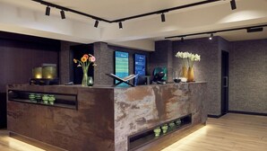 A reception desk with a rustic design, a digital display, and a vase with flowers. - Hotel Gorinchem (Gorinchem)