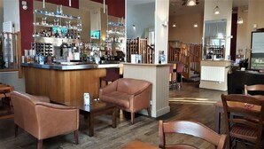 Eine Bar mit Ledersesseln, einer Theke mit verschiedenen Flaschen und einem Fernsehbildschirm.