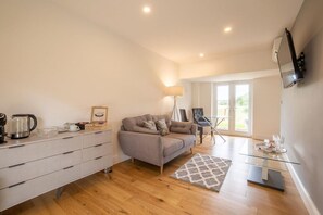 Un salon moderne avec un canapé, une table basse en verre, une lampe et un téléviseur fixé au mur.