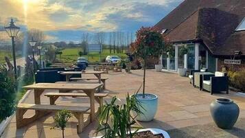 An outdoor patio area with picnic tables, potted plants, and a reception sign.