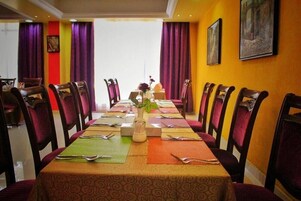 A dining area with a long table set for a meal, surrounded by chairs, with a vase of flowers on the table.