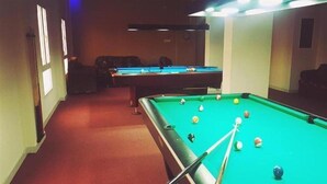 A pool table with balls, a cue stick, and a red carpeted hallway. - Royal Garden Hotel (Sohar)