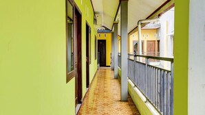 Ein Korridor mit grünen Wänden, einem gefliesten Boden und einem Balkon mit Metallgeländer.