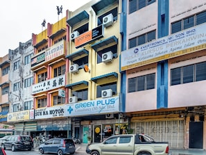 Un immeuble à plusieurs étages abritant divers commerces, notamment un hôtel, une société de conseil et un magasin de pièces automobiles.