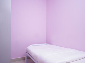 Une petite chambre avec un lit simple, un lit blanc et un mur rose.