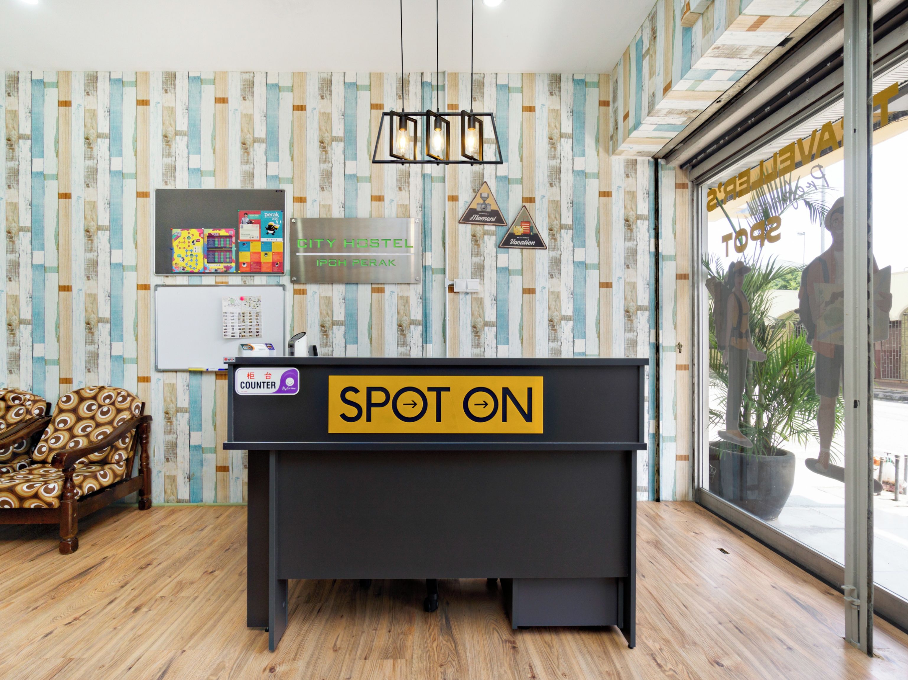 Un mostrador de recepción con un cartel que dice 'SPOT ON', una barra, una silla, una pared con papel tapiz a rayas y un ventanal con una estatua.