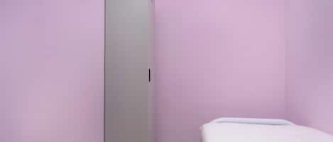 A small room with a single bed, a wardrobe, and a tiled floor.