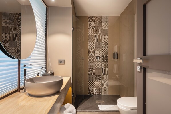 A modern bathroom with a large vessel sink, a glass shower enclosure, and a patterned tile backsplash. - Pietra D'acqua Natural Retreat and Spa Resort (Scicli)