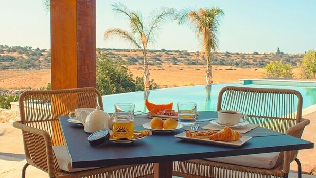 A table set for breakfast with a view of a desert landscape and a pool. - Pietra D'acqua Natural Retreat and Spa Resort (Scicli)