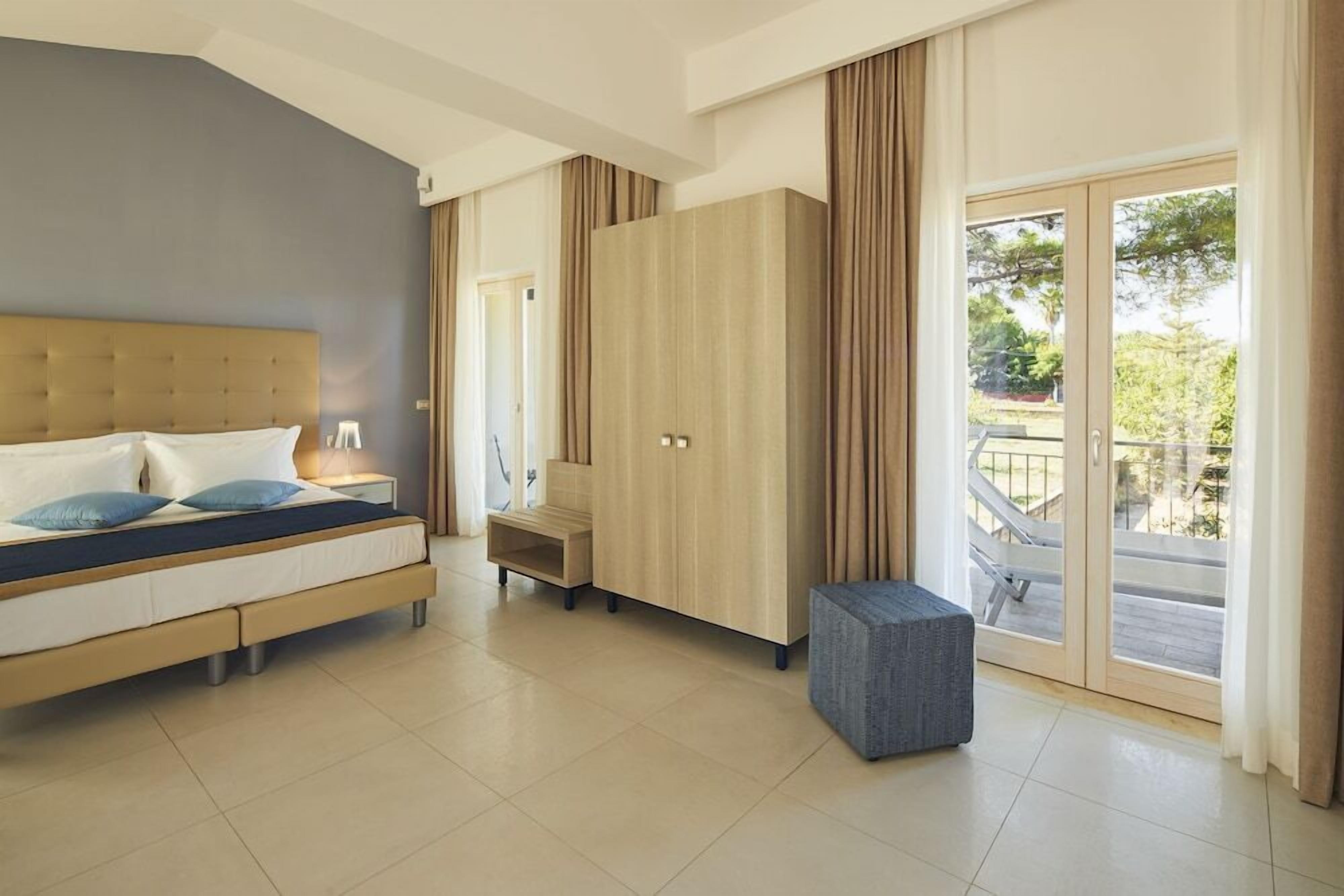 A modern bedroom with a bed, wardrobe, and a small seating area.