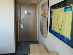 A hallway with a wooden door, a bench, and a wall-mounted rack with hangers. - Thank (Shanghai)