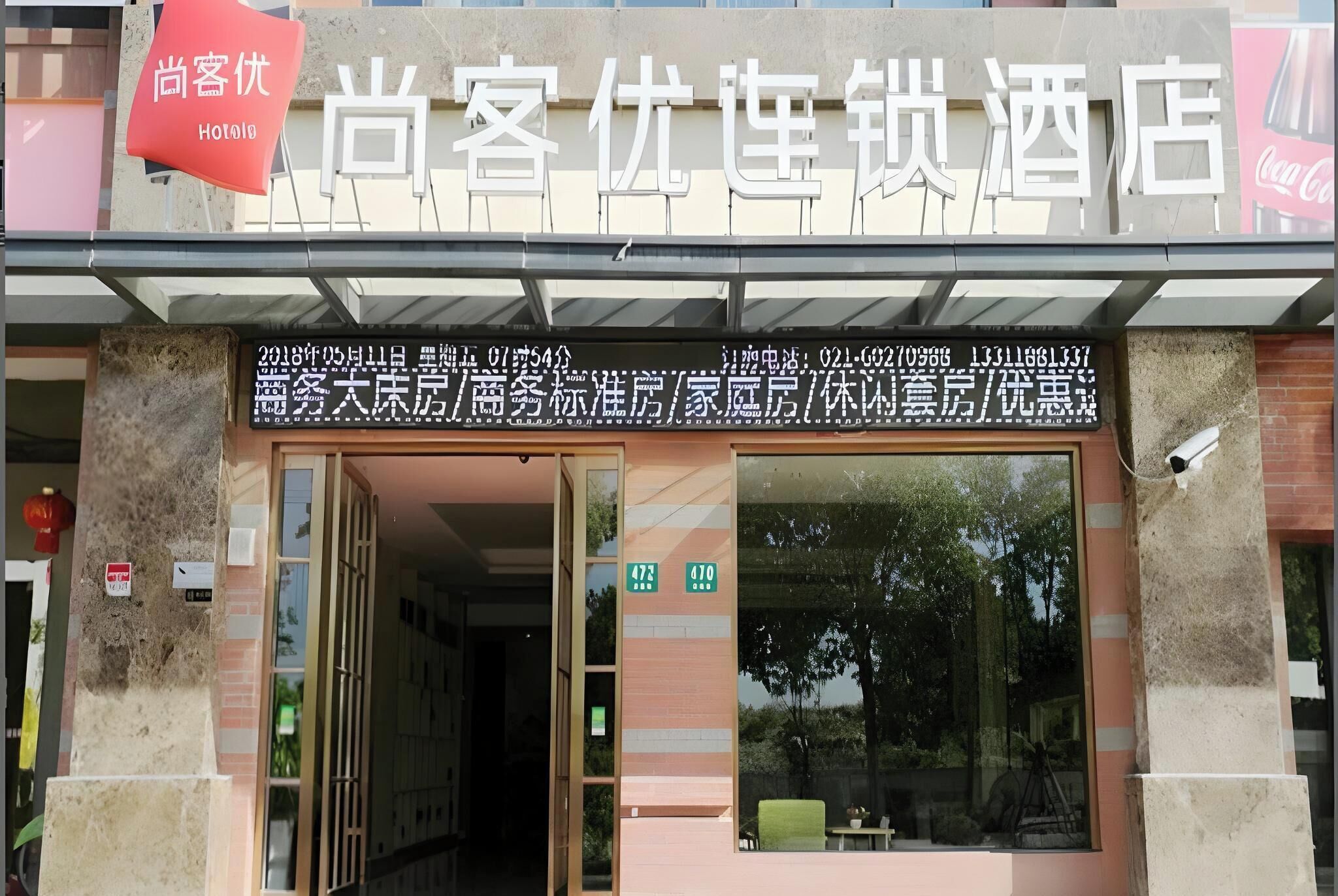 A hotel entrance with a signboard displaying room numbers and contact information.