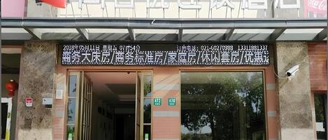 A hotel entrance with a signboard displaying room numbers and contact information.