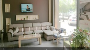 A modern living room with a sectional sofa, a coffee table, and a TV mounted on the wall. - Thank (Shanghai)