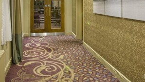 A hotel hallway with patterned carpet, a large chandelier, and a framed landscape painting on the wall. - Glenburn Hotel (Rothesay)