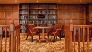 A library with bookshelves, a wooden table, and leather chairs. - Glenburn Hotel (Rothesay)