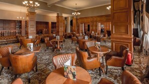 A spacious hotel lobby with leather seating, wooden paneling, and chandeliers. - Glenburn Hotel (Rothesay)