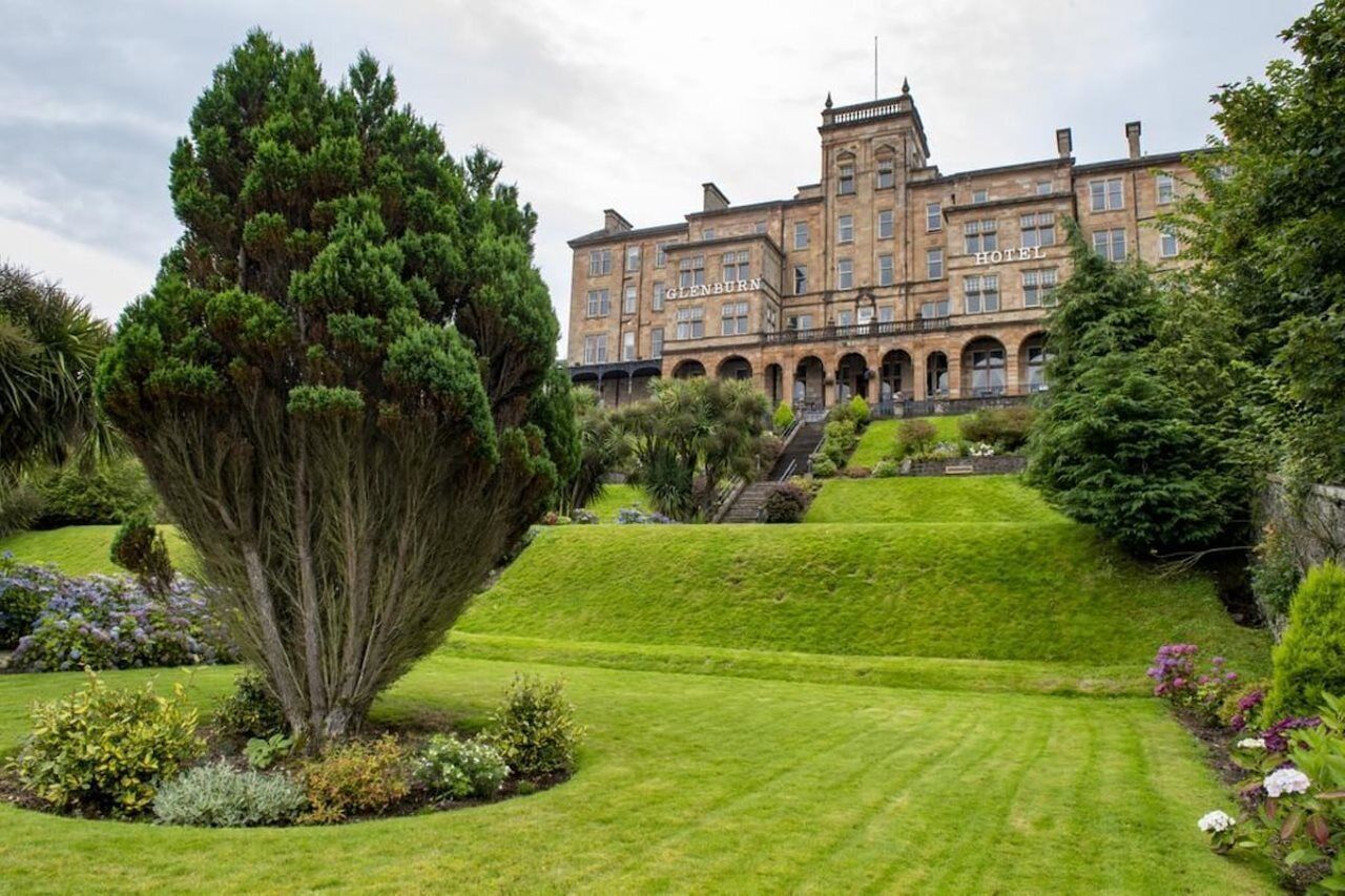 A historic hotel with a large, symmetrical facade, arched windows, and a central staircase leading to the entrance.