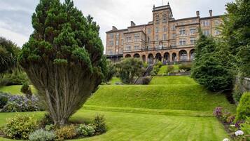 A historic hotel with a large, symmetrical facade, arched windows, and a central staircase leading to the entrance.