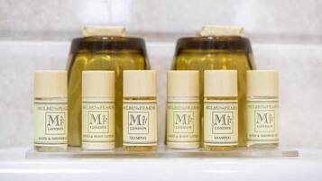 A row of six bottles of M&F London bath and shower gel, with two larger bottles of M&F London shampoo behind them.