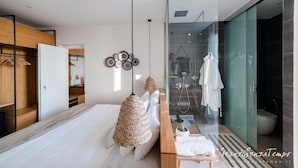 A modern bedroom with a bed, bedside table, hanging lamps, and a glass shower enclosure. - Cumeja Beach Club Hotel (Cellole)