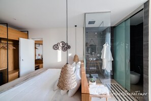 A modern bedroom with a bed, bedside table, hanging lamps, and a glass shower enclosure. - Cumeja Beach Club Hotel (Cellole)