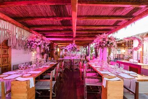 A restaurant with wooden tables and chairs, pink floral decorations, and a warm ambiance. - Cumeja Beach Club Hotel (Cellole)