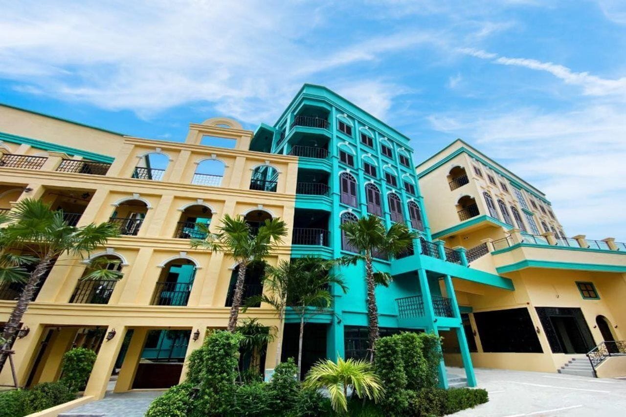 A multi-story hotel with a central atrium, balconies, and palm trees.