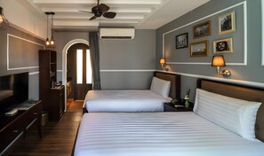 A hotel room with two beds, a TV, a desk, a wardrobe, and a ceiling fan. - Quba by Montraj Pattaya (Pattaya)