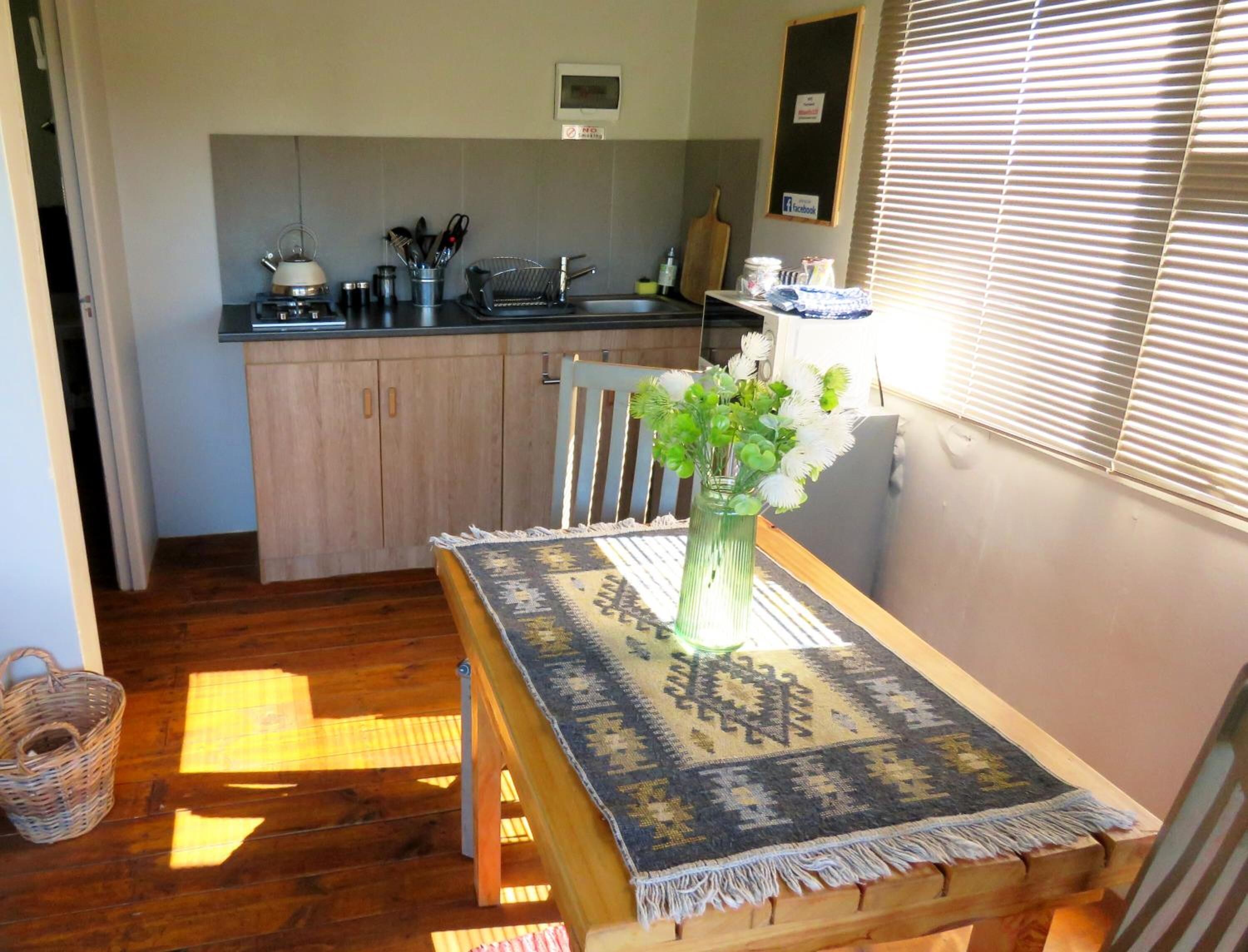 A cozy kitchen with wooden cabinets, a sink, and a dining area with a table set for two.