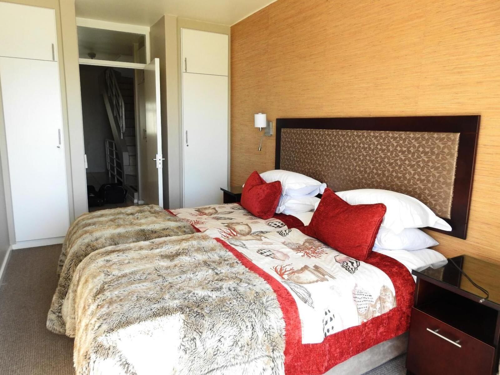 A hotel room with a large bed, two bedside tables, a wardrobe, and a mirror.