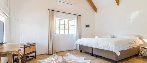 A bedroom with a large bed, a desk, a cowhide rug, and a chandelier.