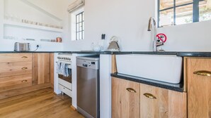 Eine moderne Küche mit Holzschränken, einem Geschirrspüler, einem Herd und einer Spüle.
