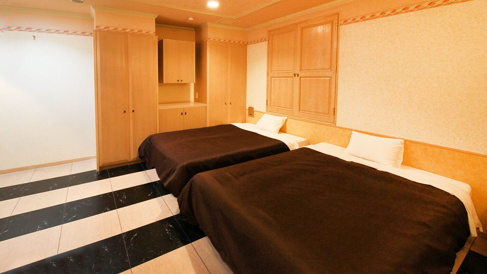 Habitació d'hotel amb dos llits, un bany amb mirall i un armari.