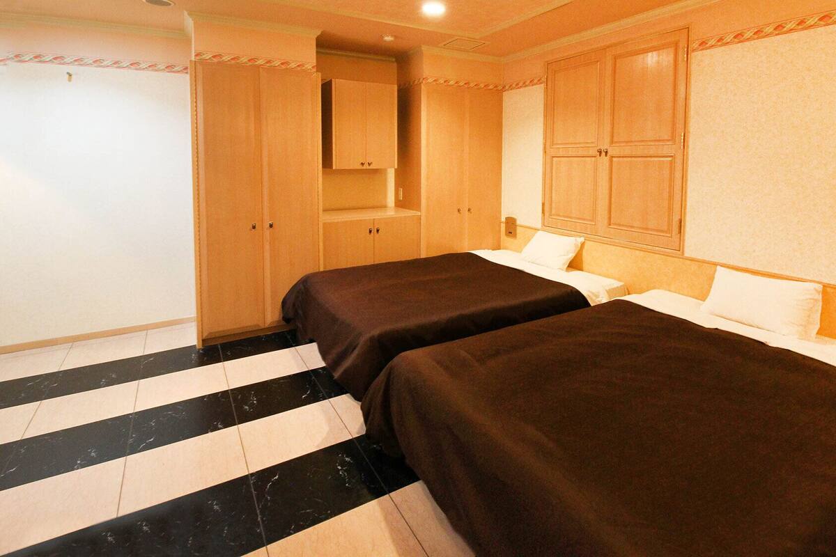 Une chambre d’hôtel avec deux lits, une salle de bain avec un miroir et une armoire.