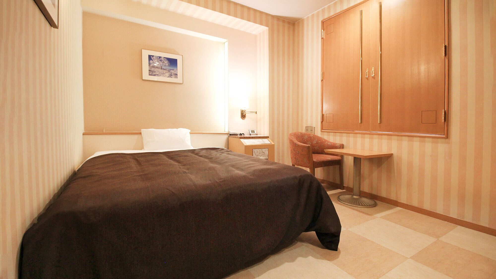 Habitació d'hotel amb un llit, escriptori, cadira i armari.
