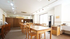 A conference room with wooden tables and chairs, a kitchenette, and a large window. - Hotel San Marco (Daito)
