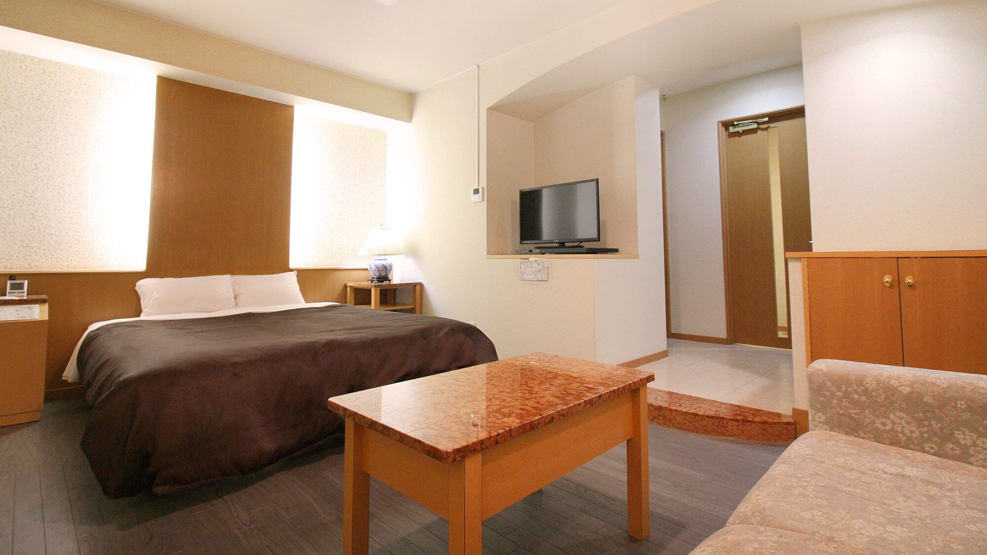 Habitació d'hotel amb llit, televisió, escriptori i armari.