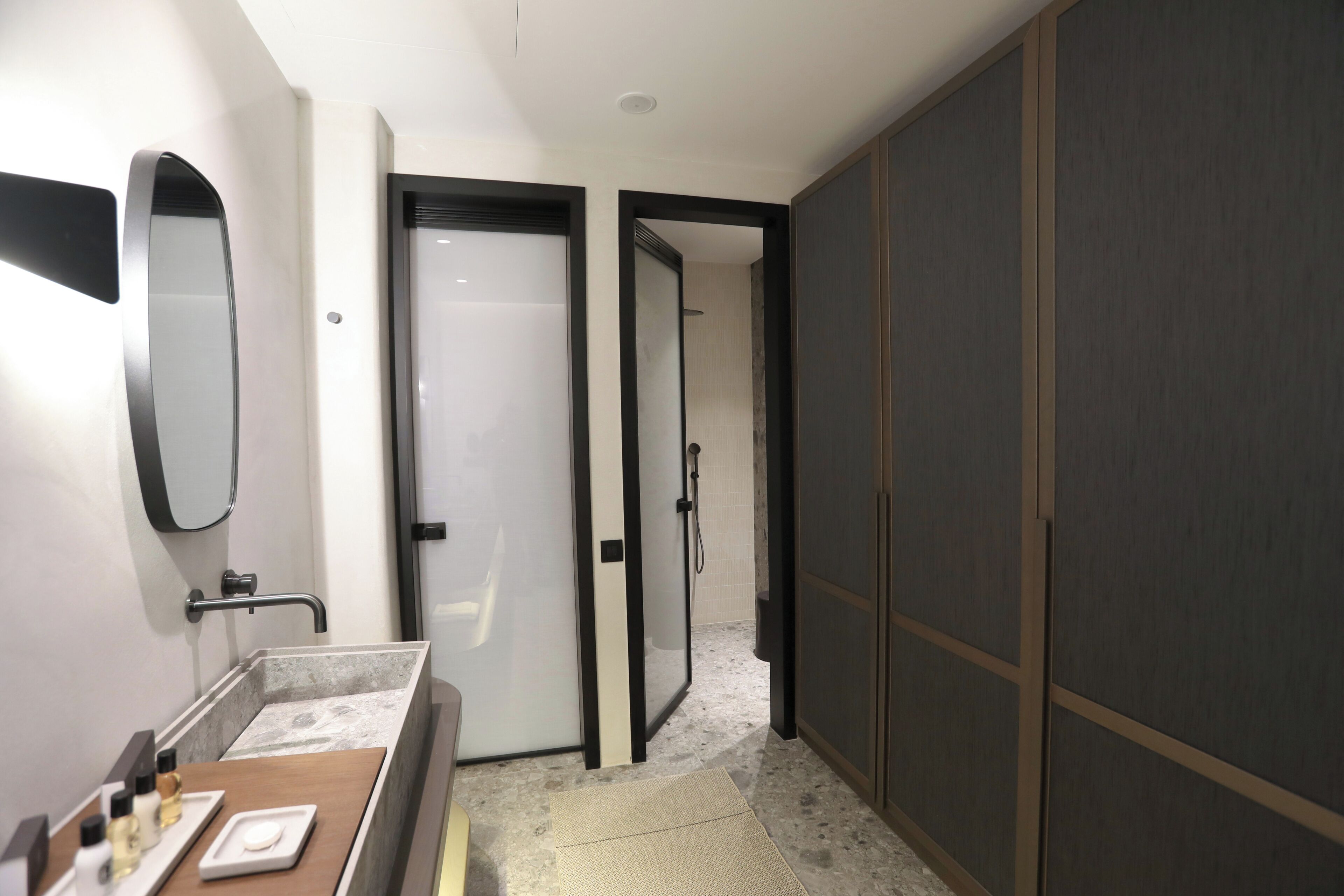 A modern bathroom with a vanity, mirror, and shower area.