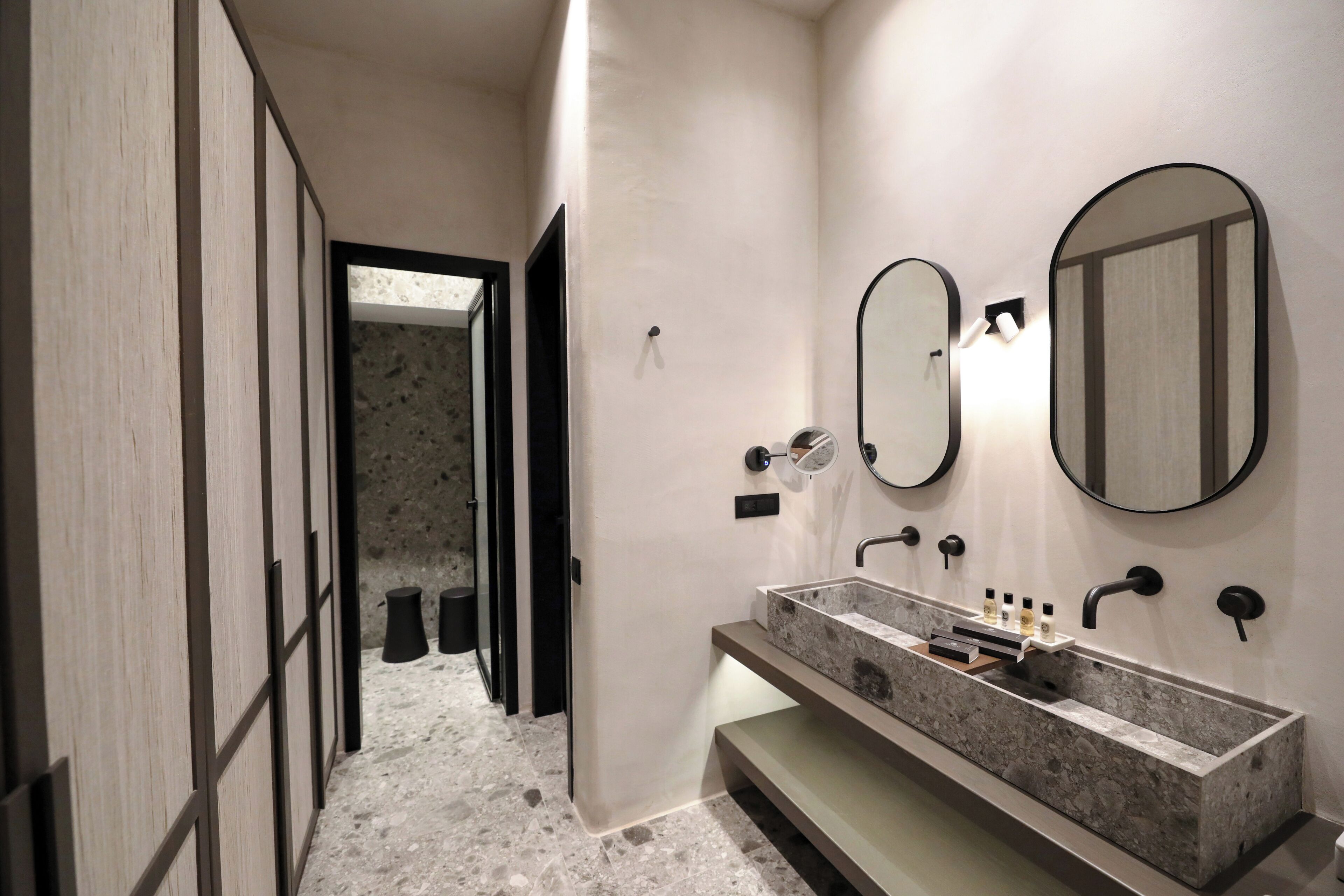 A modern bathroom with a rectangular sink, two wall-mounted mirrors, and a door leading to another room.