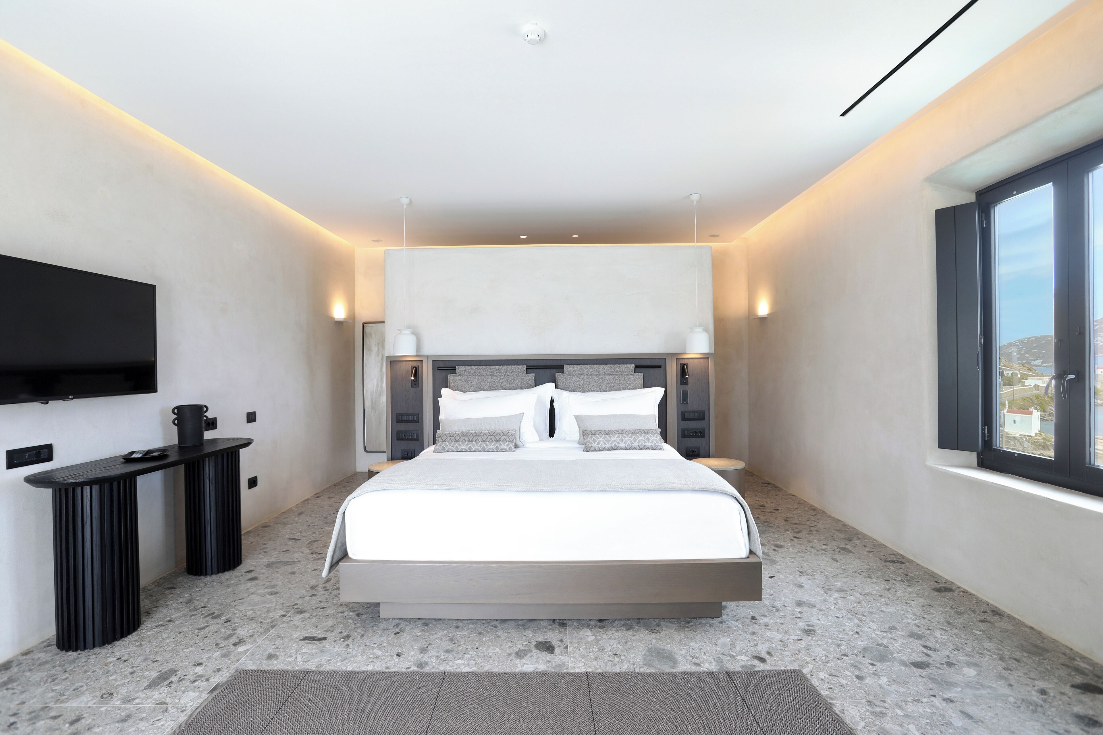 Une chambre moderne avec un grand lit, des tables de chevet, un téléviseur à écran plat et une fenêtre donnant sur un beau paysage.
