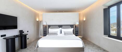 Une chambre moderne avec un grand lit, des tables de chevet, un téléviseur à écran plat et une fenêtre donnant sur un beau paysage.