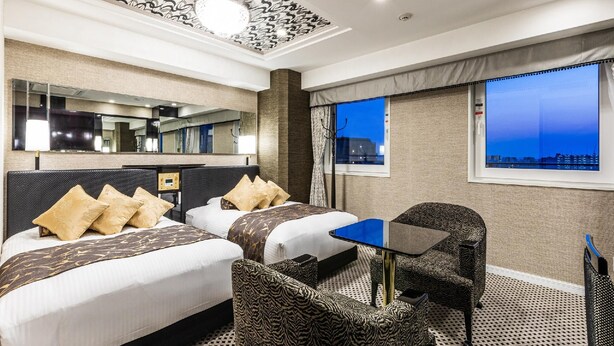 A hotel room with two beds, a desk, a chair, a small table, a mirror, and a window with a city view. - APA Hotel Nanbaminami Ebisucho-eki (Osaka)