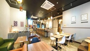A modern cafe with wooden tables and chairs, a bar area, and artwork on the walls. - APA Hotel Nanbaminami Ebisucho-eki (Osaka)