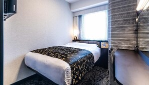 Una habitación de hotel con cama, ventana con cortinas, mesita de noche y panel de control en la pared.