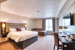 A hotel room with a large bed, a desk, a chair, a sofa, and a TV. - Premier Inn Newquay (Newquay)